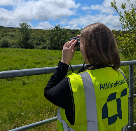 Caroline using binoculars to survey a rural landscape 