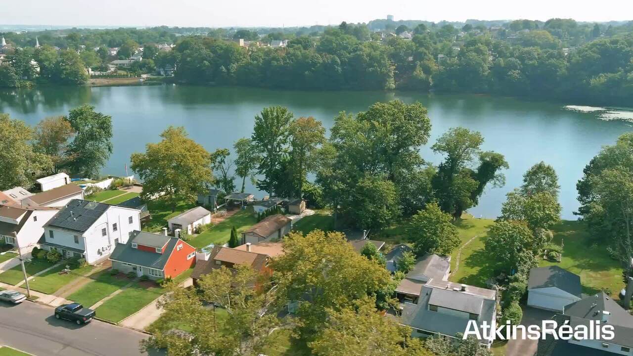 Aerial view of houses by a river with trees and the AtkinsRéalis logo.