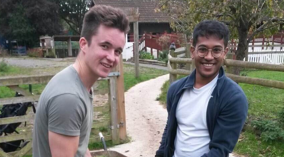 two people carrying some grass