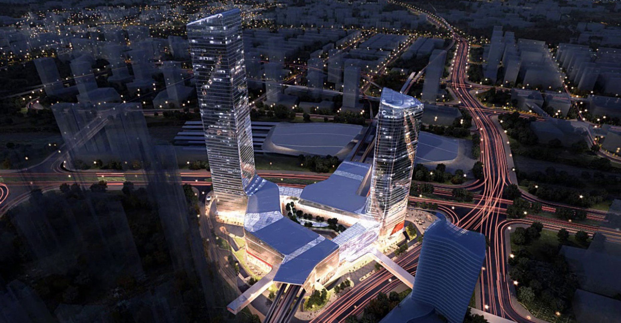 Aerial night view of a modern cityscape with illuminated skyscrapers and complex road networks, showcasing a futuristic architectural development with connected buildings and dynamic lighting.