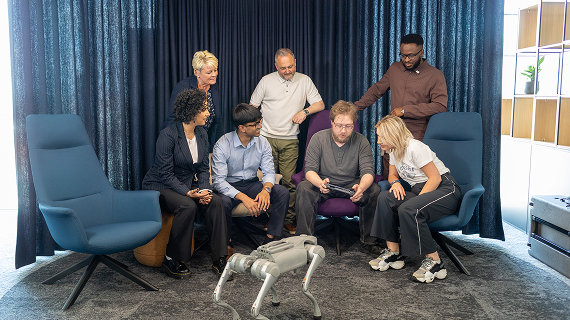 Team gathered around a robot, observing a demonstration.