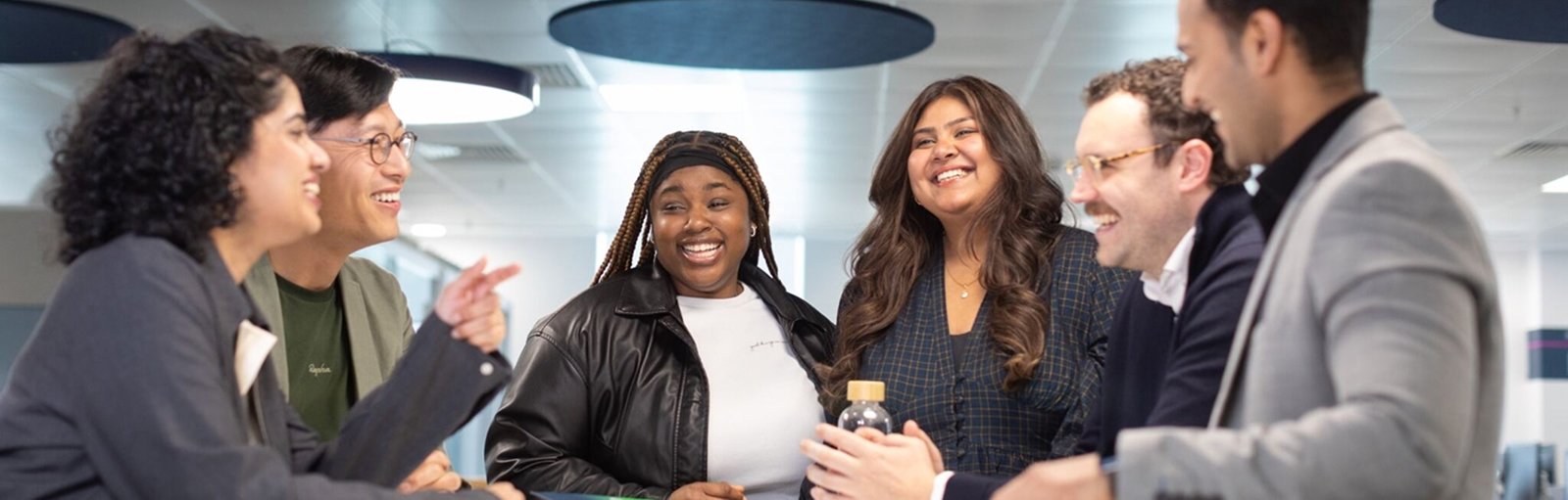 goup of coworkers smiling and talking around a table.