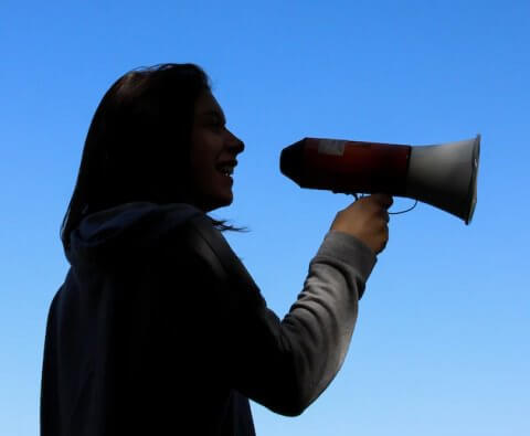Silhouette of a woman using a megaphone, symbolizing advocacy or public speaking.