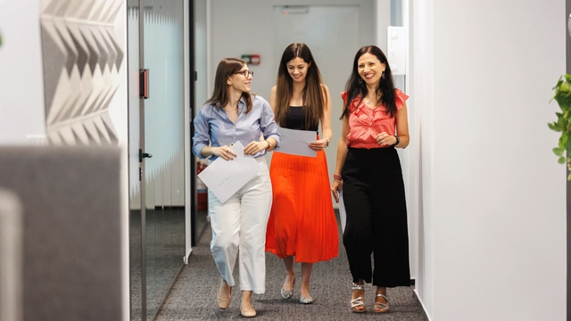 Three professionals walking together in office corridor