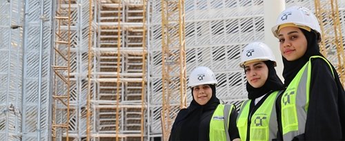 Three women in hard hats on site