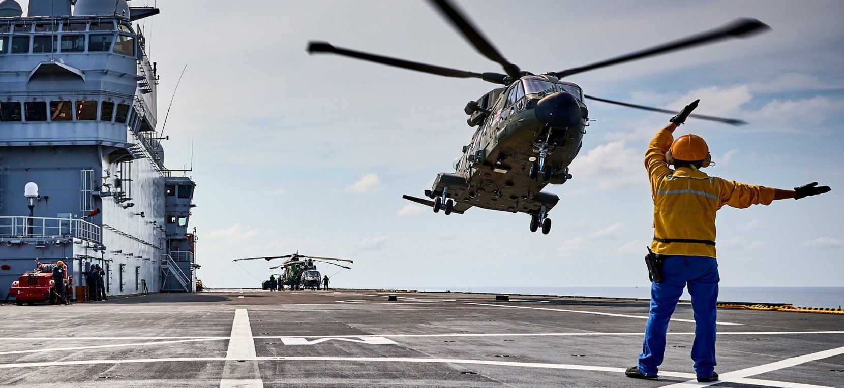 A man give direction to helicoptor for landing.