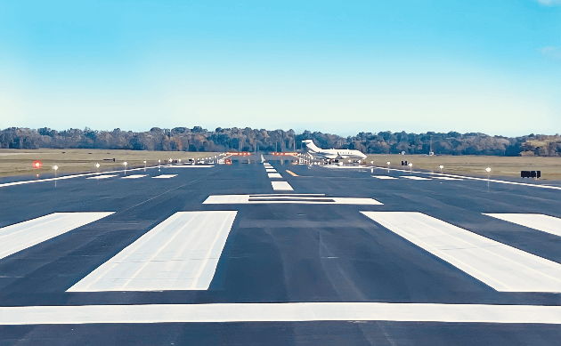 Airport runway with aircraft parked in distance