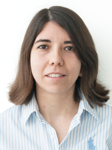 Portrait of a woman with shoulder-length brown hair, wearing a light blue and white striped shirt, standing against a plain white background.