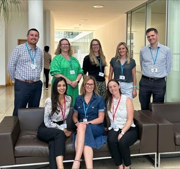 Group of employees smiling with children in an outdoor setting