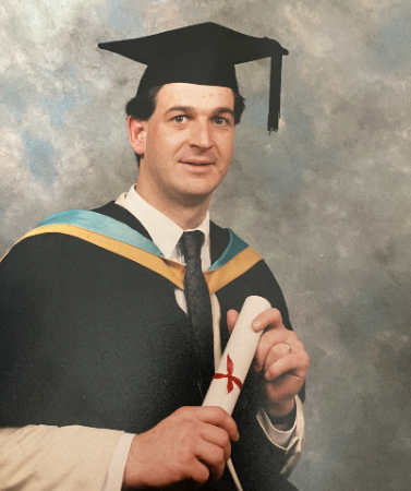 A picture of Adam Brooks in a suit smiling.