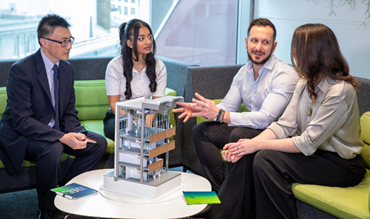 A group of colleagues talking to each other, with a building model placed in front of them