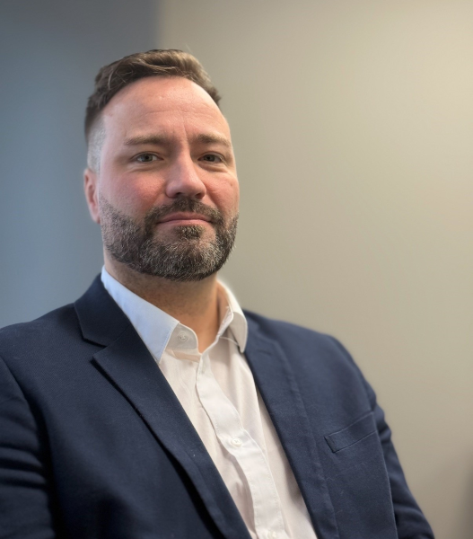 Man in a navy blazer and white shirt posing for a professional portrait.