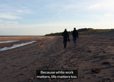 A picture of two people walking by the beach