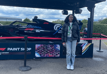 Person standing in front of a black Formula 1 car display under a canopy.